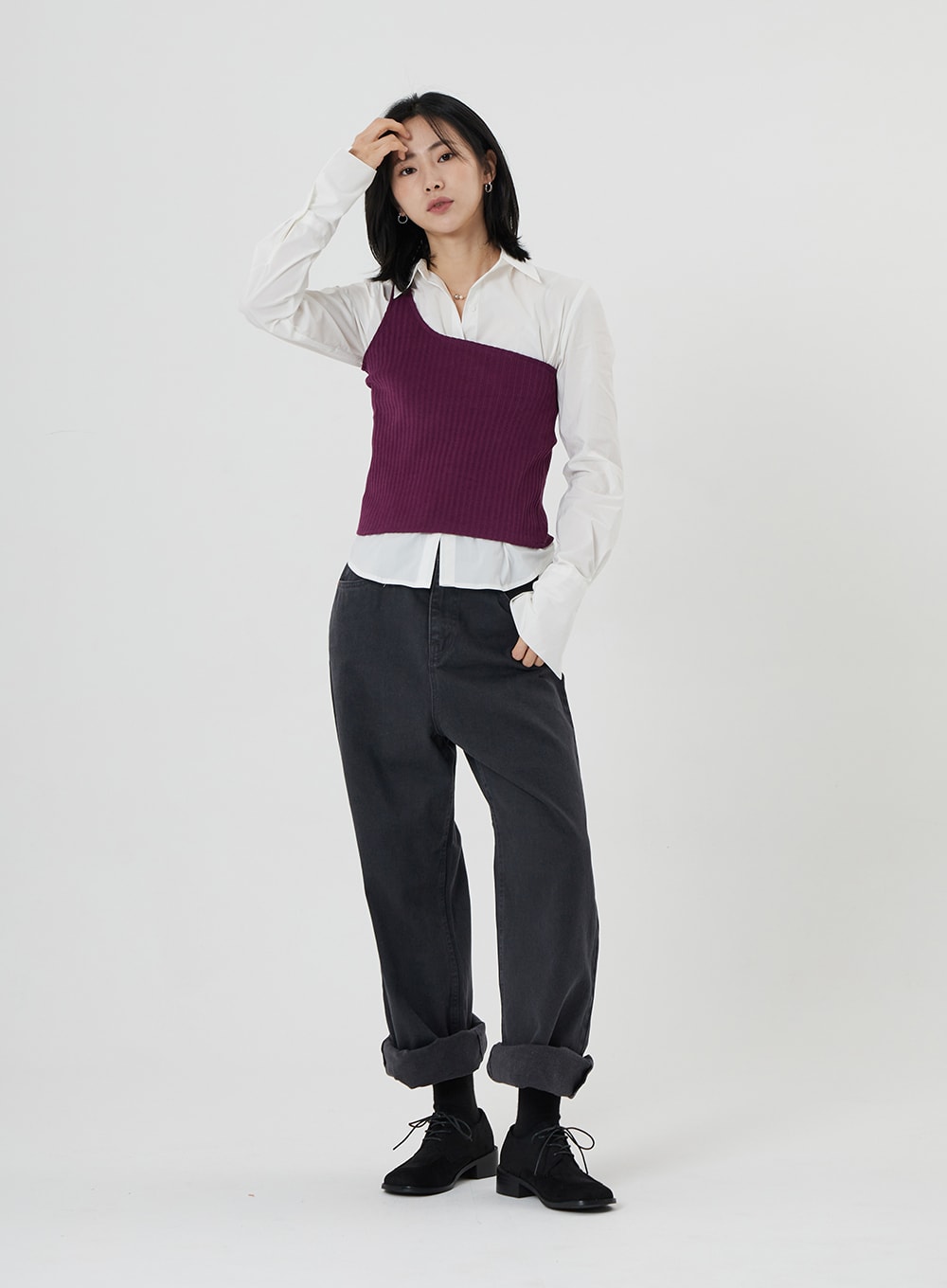 Maxi Denim Pants ON23 in charcoal grey, full-body front shot on model with hand raised, wide-fit denim with turned-up cuffs, paired with white shirt and asymmetric purple knit vest.
