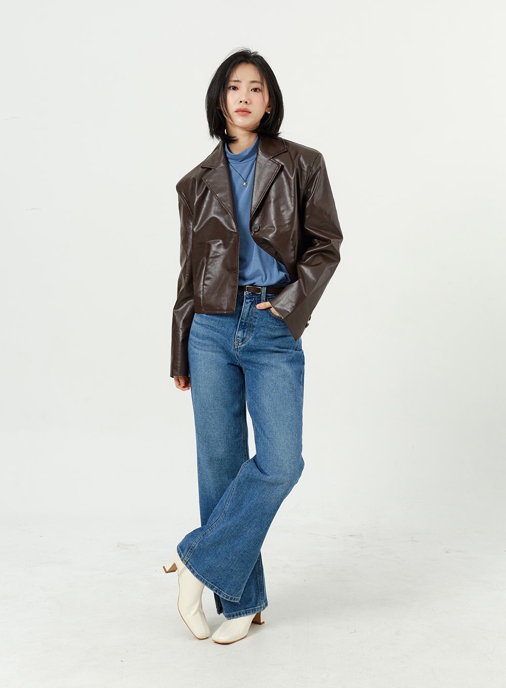 Side Slit Jeans OM308 in mid blue, full-length front angled shot on model, wide-fit cotton denim, paired with dark brown leather jacket and white heeled boots.