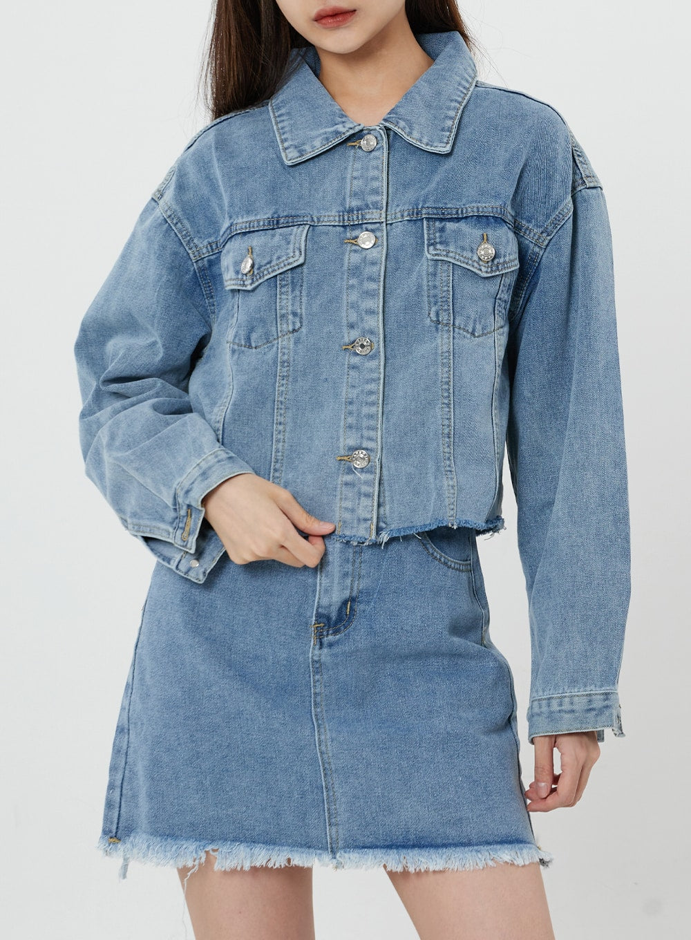 Sienna Crop Jeans Jacket CS21 in light blue, front close-up on model, dual chest flap pockets and silver button closure visible, worn open over denim mini skirt.