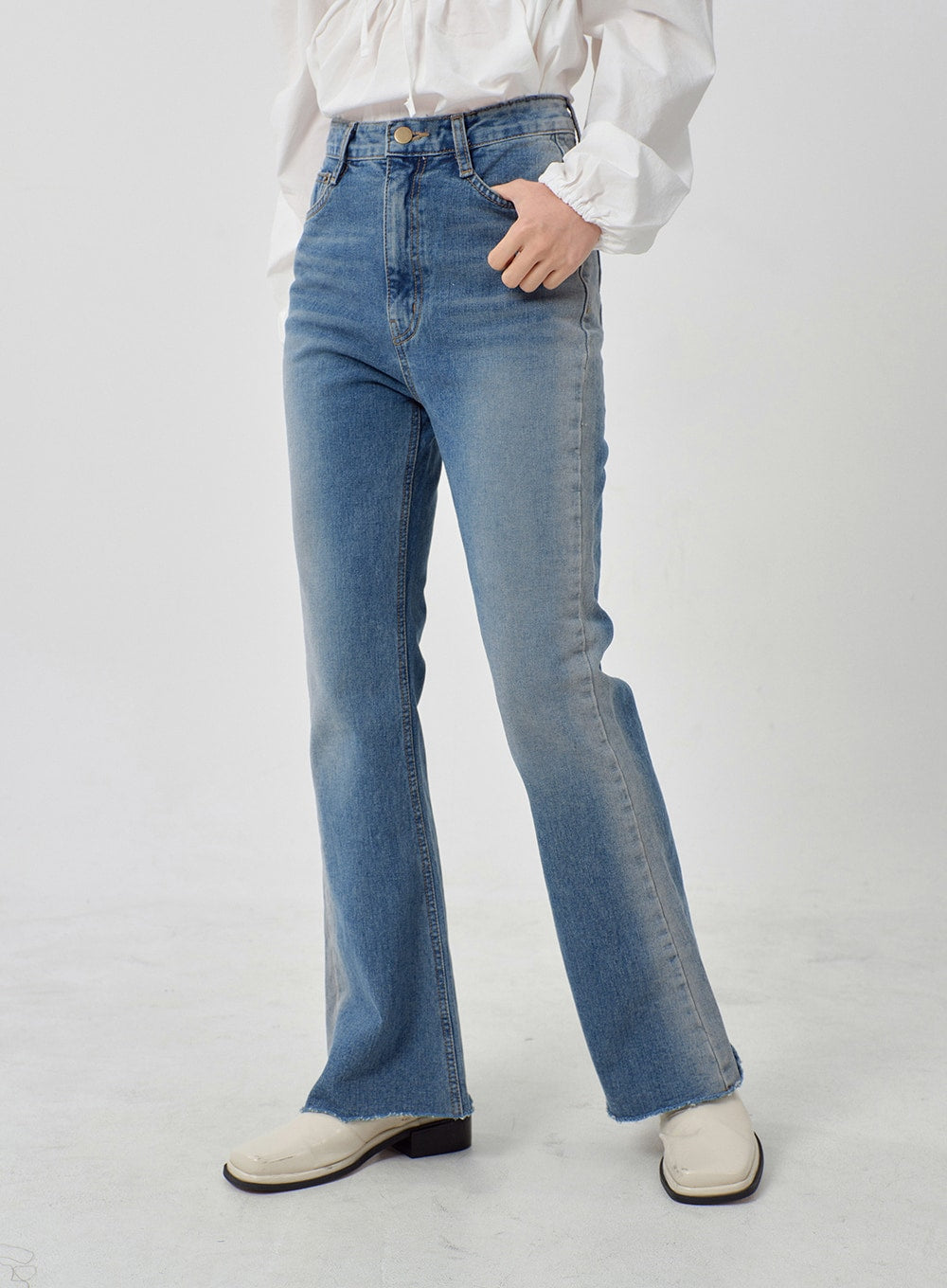 Light Washed Bootcut Jeans OD27 in light blue, front waist-to-hem close-up on model, high-rise five-pocket design, gold button closure, slim leg with subtle washed finish and raw frayed hem.