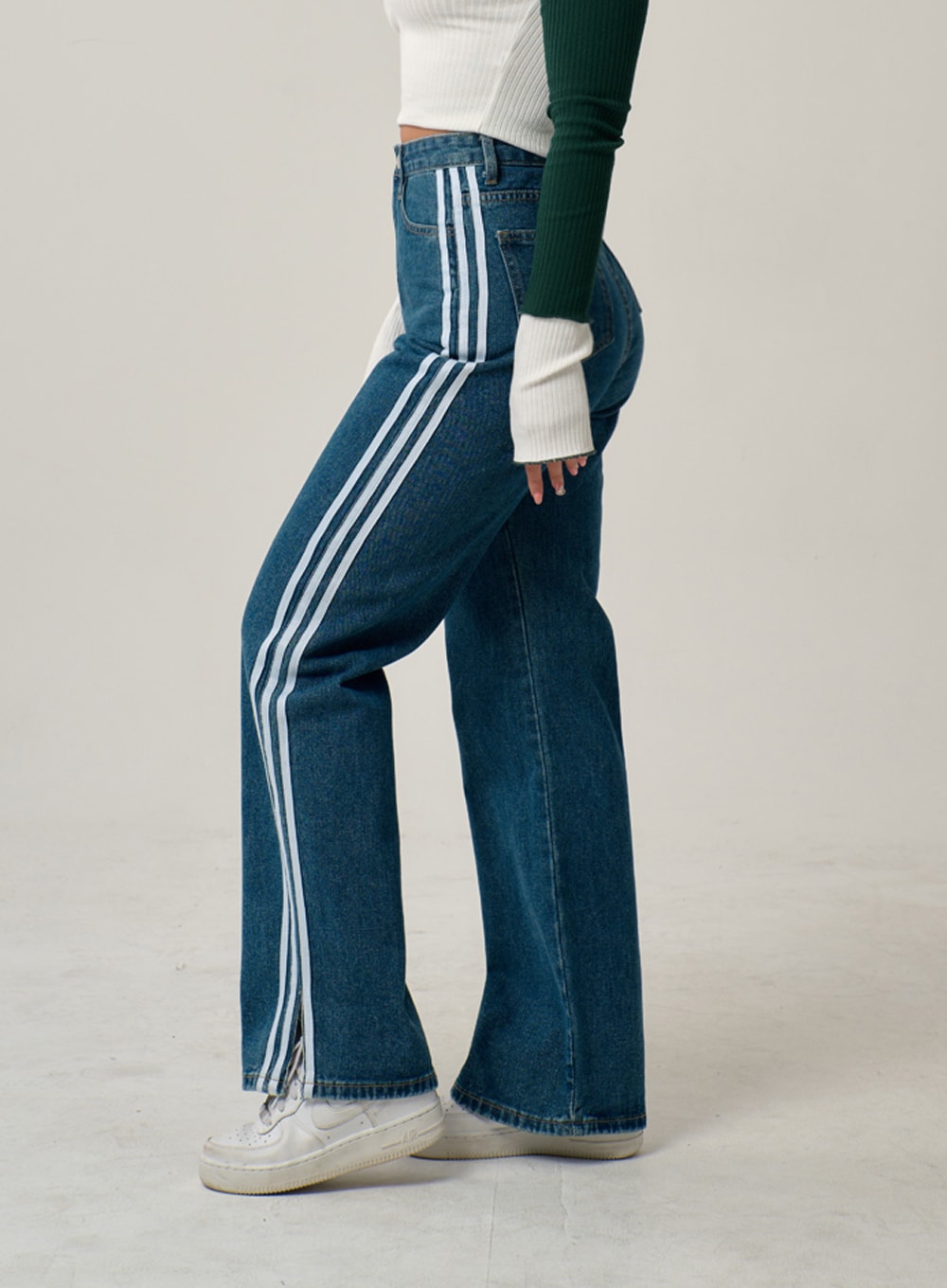 Side Stripes Straight Leg Jeans IN22 in mid blue, side view on model showing three white vertical stripes running full length, wide-leg cotton denim with cut-out hem detail at ankle.