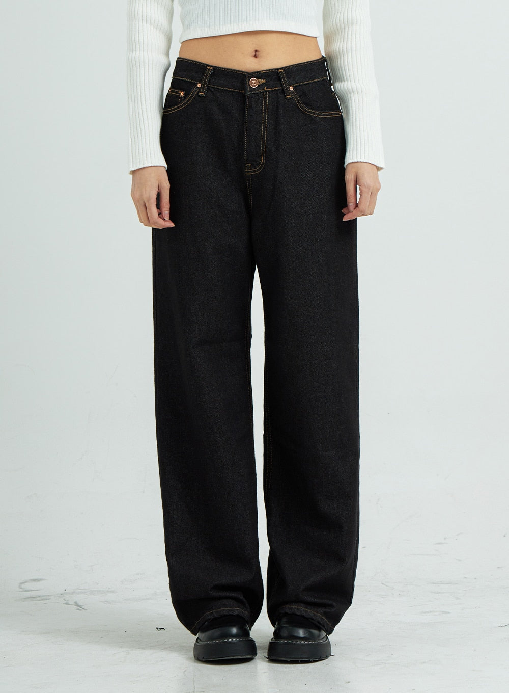 Pepe Wide Pants CS15 in black, front close-up on model, wide-fit cotton denim with gold contrast topstitching and copper hardware, paired with white crop top.