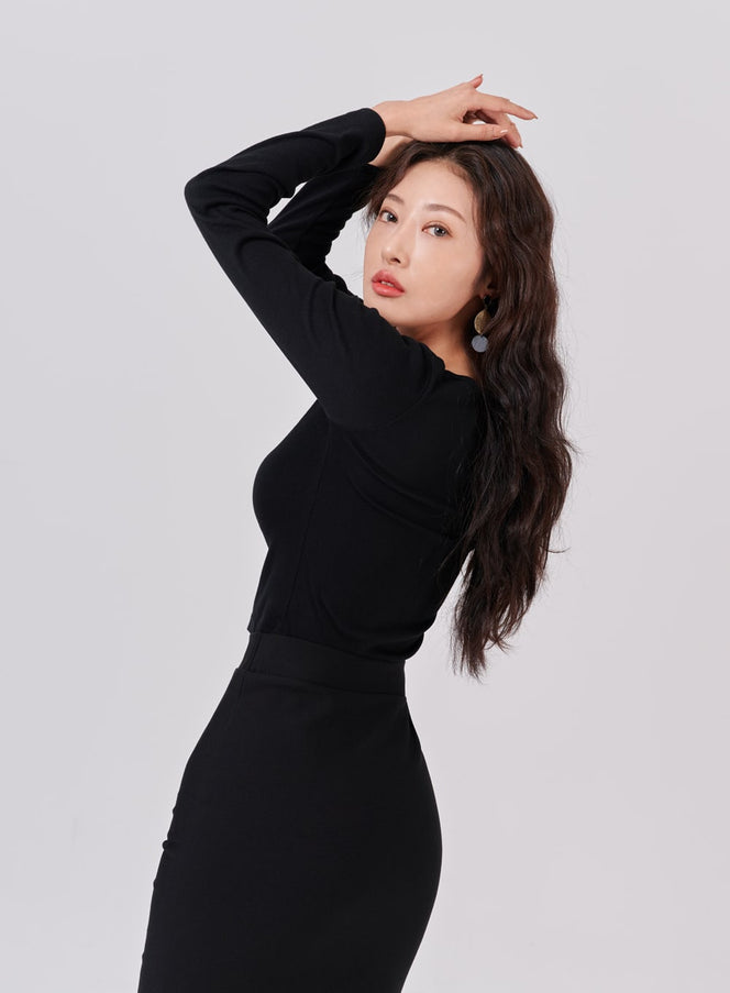 Square Neck Crop Long Sleeve T-Shirt IS05 in black, angled front-side view on model with arms raised, slim crop silhouette, styled with a black pencil skirt.