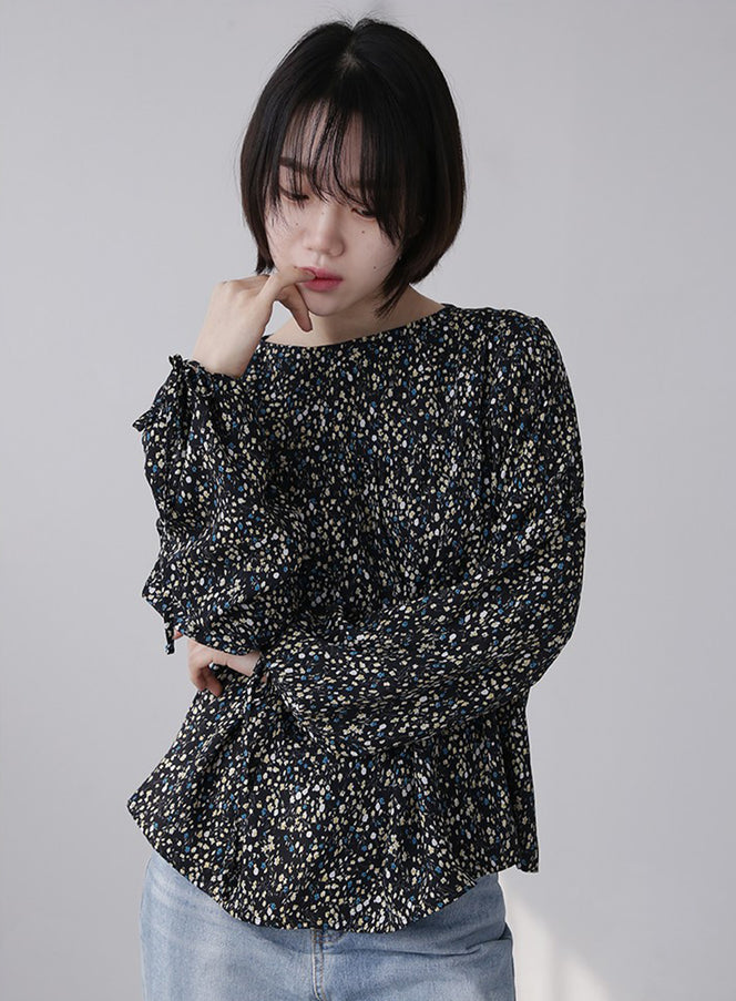 LEWKIN Shirring Blouse in black floral print, front three-quarter view on model, wide-fit short polyester blouse with shirring bodice, long sleeves, paired with light blue jeans.