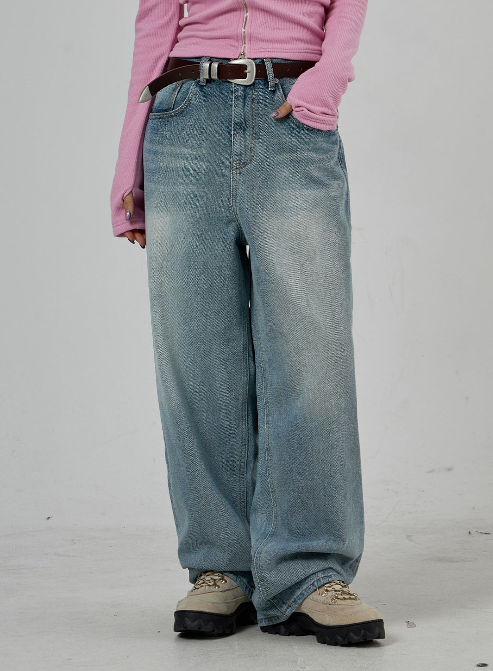Light Wash Baggy Jeans Unisex CD26 in light blue, waist-to-hem front close-up, washed denim with faded whisker detail, wide leg silhouette, brown belt and chunky sneakers.