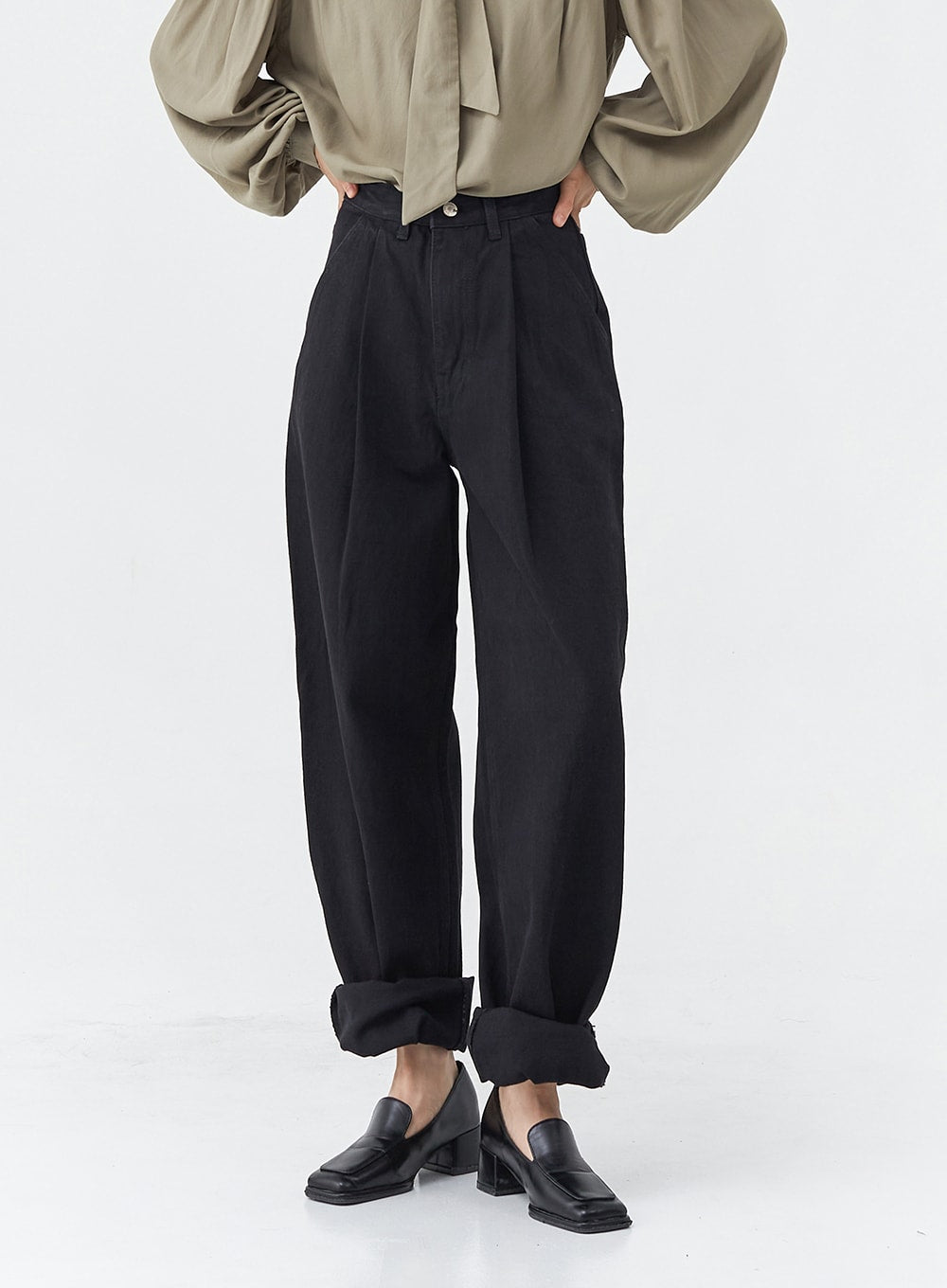 Pintuck Black Jeans OG18 in black, waist-to-hem front close-up on model, high-rise wide-fit cotton with front pintuck creases and rolled hem, paired with olive blouse.
