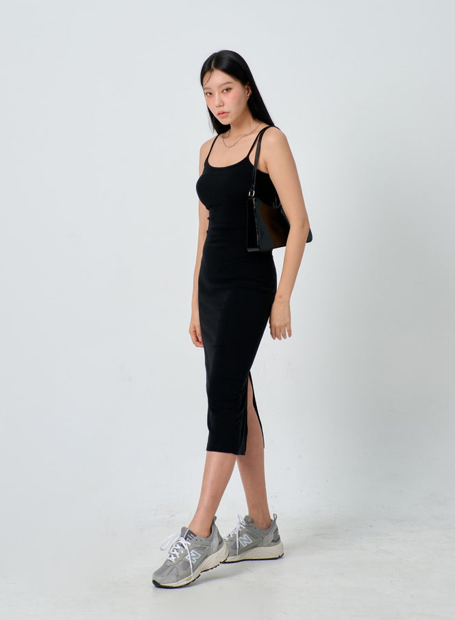 Thin Strap Maxi Dress IJ330 in black, side view on model revealing a front side slit, slim stretch silhouette with thin straps, styled with black tote bag and grey sneakers.