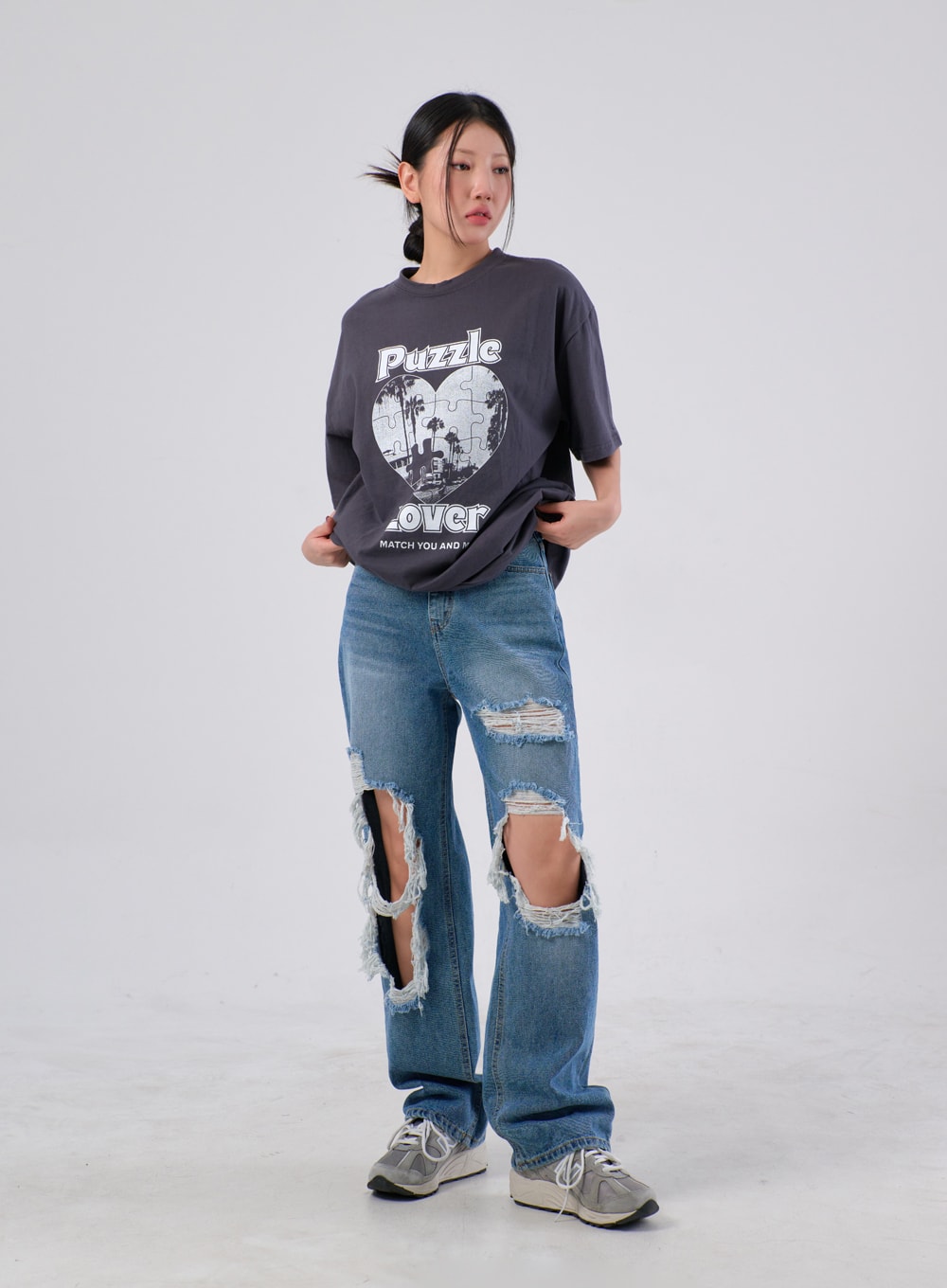 Ripped Knee Jeans IA305 in medium blue, full-body front shot on model, wide-fit street style with large frayed knee rips, styled with a grey graphic tee and grey sneakers.