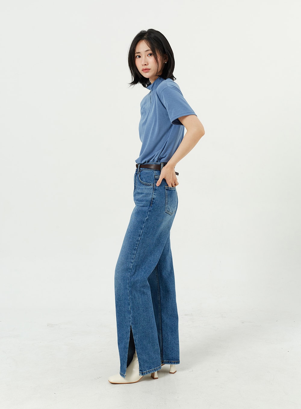 Side Slit Jeans OM308 in mid blue, full-length side profile on model, wide-leg cotton denim with side slit at hem clearly visible, model glancing back, white heeled boots.