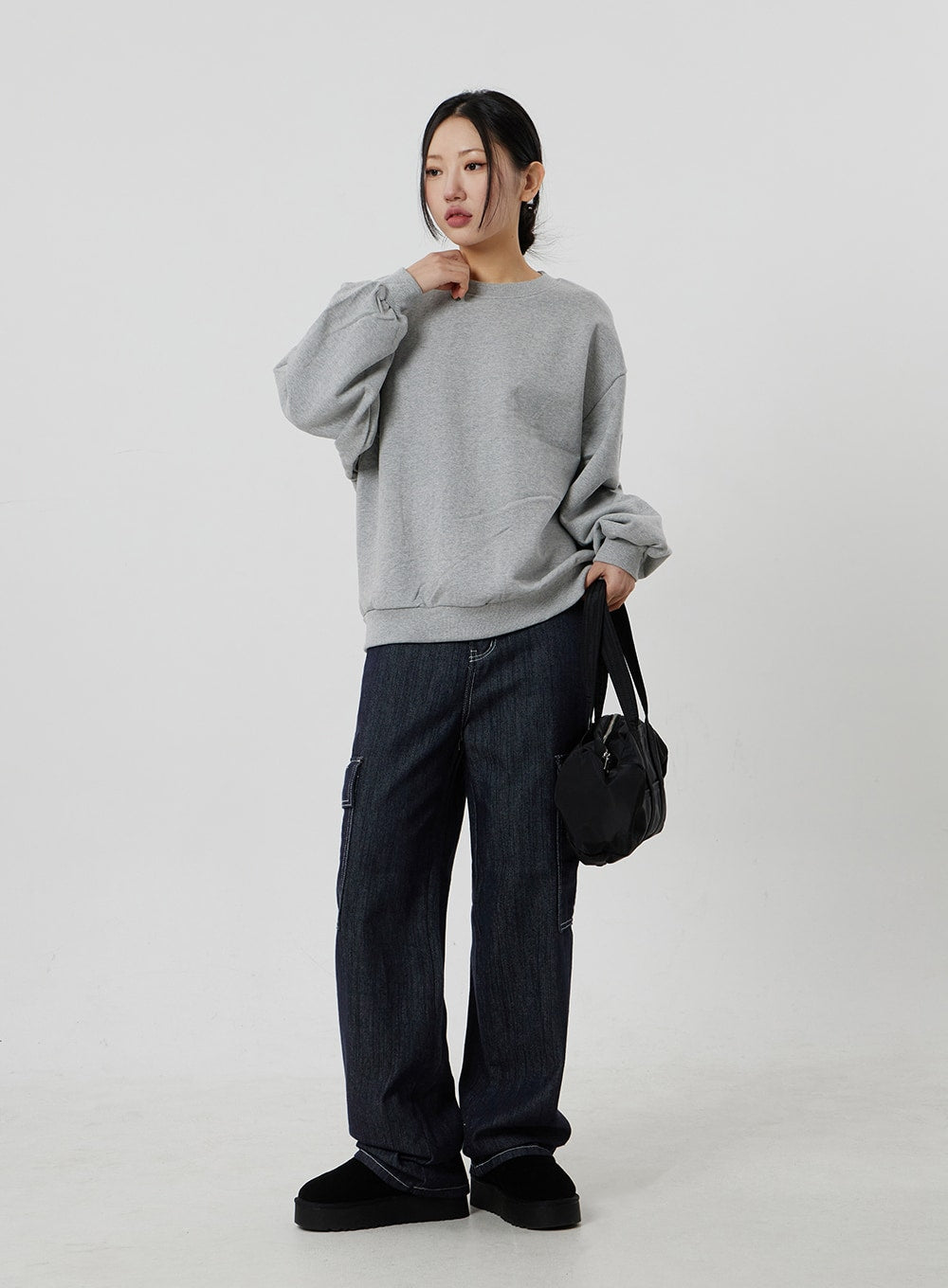 Wide Cargo Jeans CF302 in dark indigo, full-length slight-angle on model holding black bag, wide-fit denim with side cargo pockets and white contrast stitching, casual street styling.