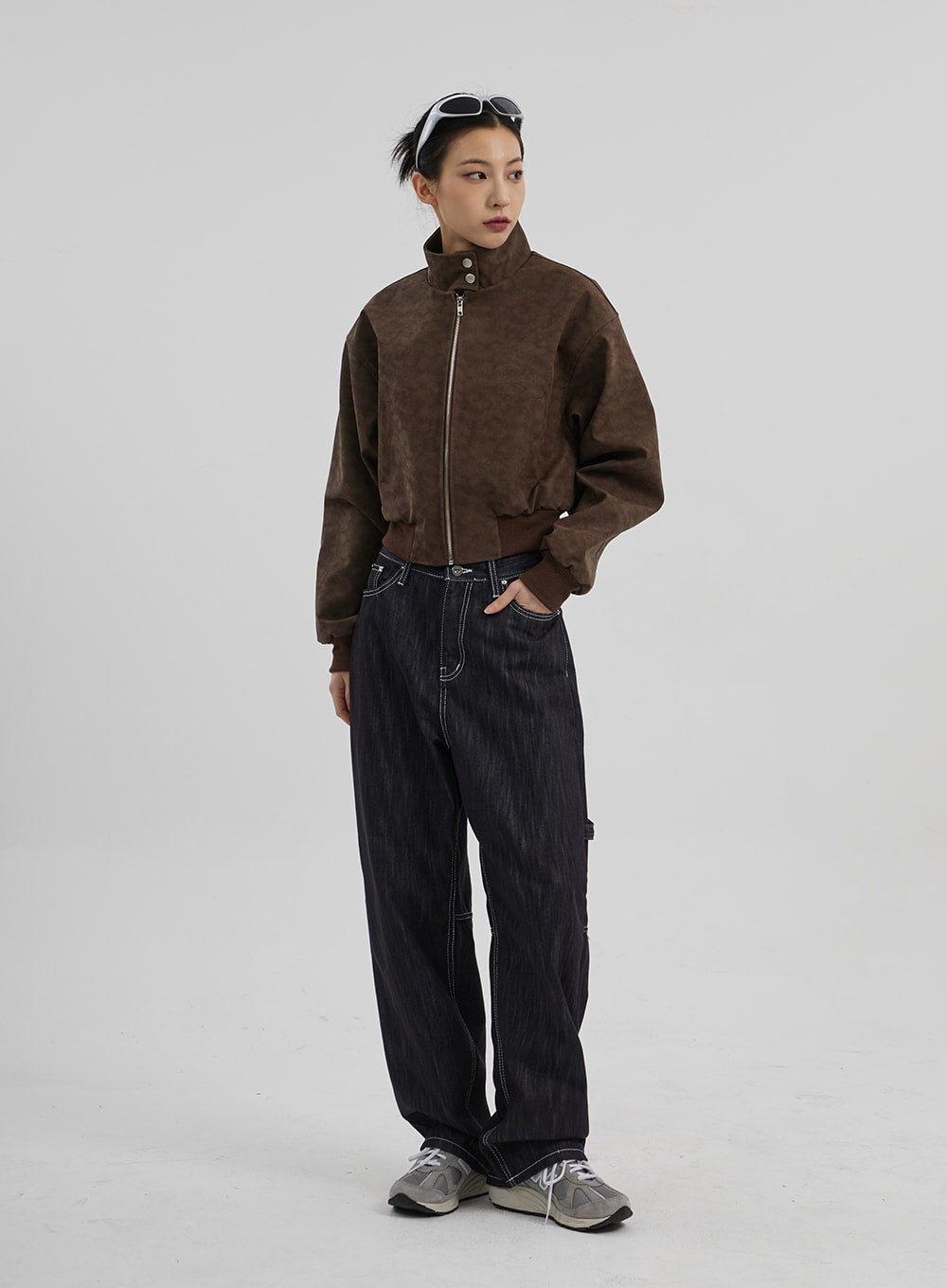 Mid-Rise Baggy Jeans CF307 in dark indigo, three-quarter front angle on model, wide-fit carpenter denim with contrast stitching, styled with brown suede bomber and chunky sneakers.