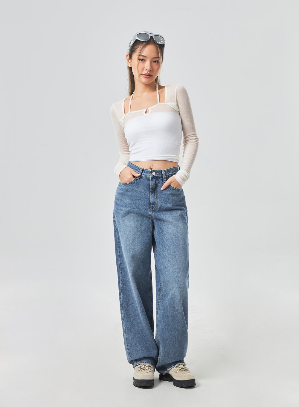 Wide Leg Mid-Wash Jeans CM331 in mid-wash blue, full-length front view on model with hands in pockets, relaxed wide-leg denim, paired with white mesh crop top and sunglasses.