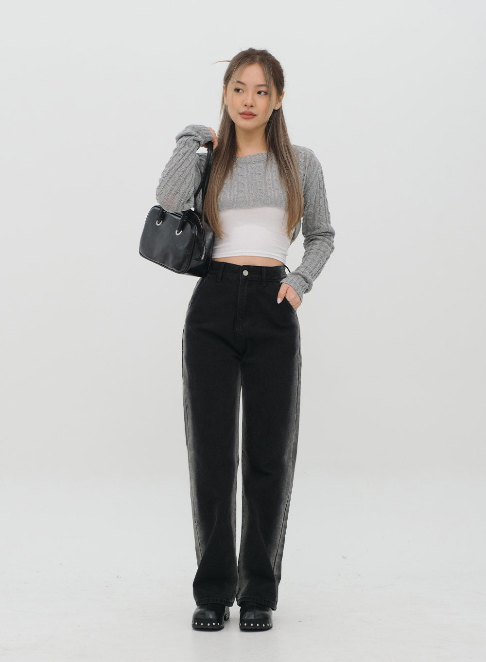 Black Jeans C1002 in washed black, full-body front shot on model standing, wide-fit long cotton denim with subtle fade, paired with grey cable-knit and white crop top.