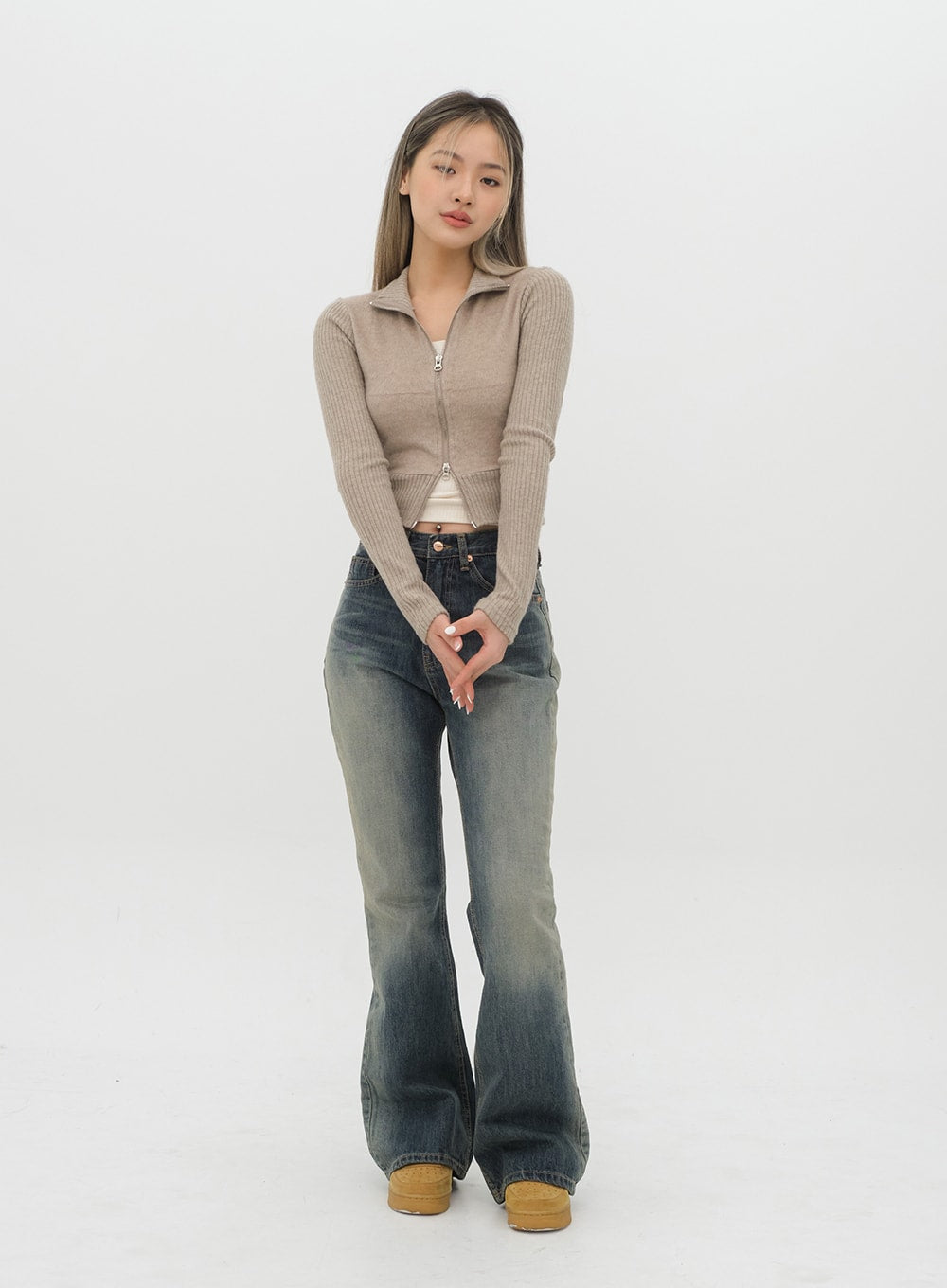Boot Cut Jeans J20 in Dark Denim, full-length front shot on model with hands clasped, gradation cotton denim flare leg, paired with beige zip-up cropped knit.