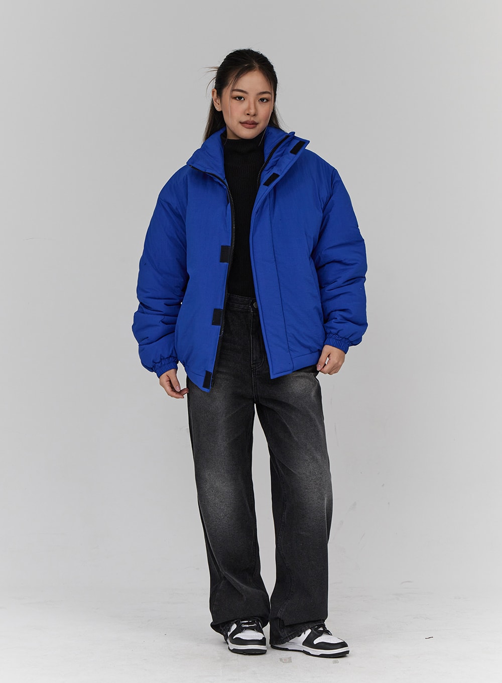 Light Washing Wide Leg Black Jeans CN23 in washed black, full-length front view on model, wide-fit cotton denim, layered under open blue puffer jacket with black turtleneck.