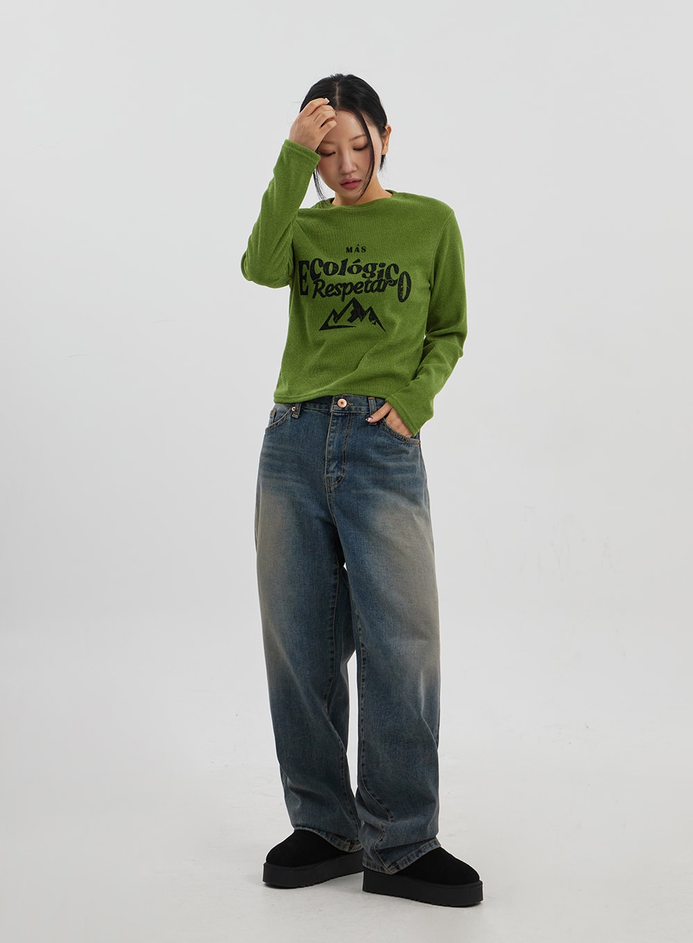 Mid-Rise Baggy Jeans Unisex CJ330 in vintage blue, full-body front view on model with relaxed pose, wide-fit faded denim, paired with green graphic knit and black platform shoes.