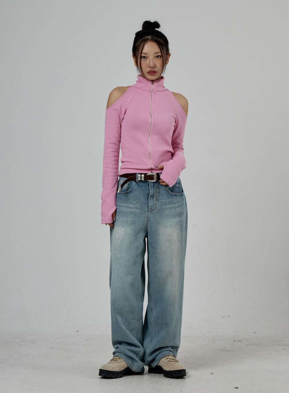Light Wash Baggy Jeans Unisex CD26 in light blue, full-body front view on model, relaxed wide-fit washed denim with floor-grazing hem, paired with pink ribbed zip top and leather belt.
