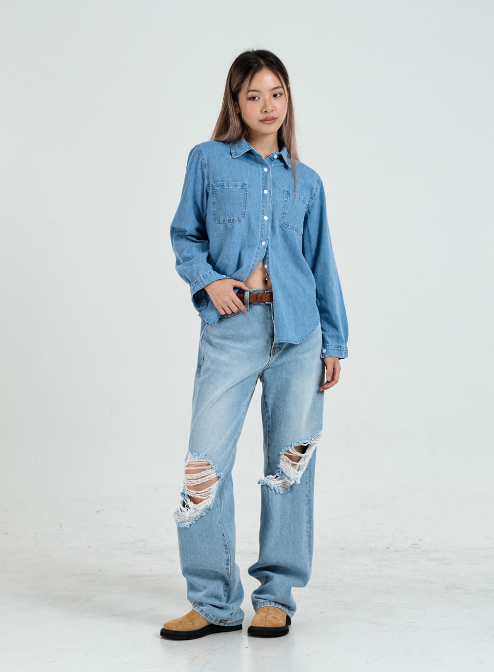 Ripped Maxi Denim Pants Unisex CO14 in light blue, full-body slight-angle front view on model, wide-leg destroyed denim, paired with oversized denim shirt and brown leather belt.