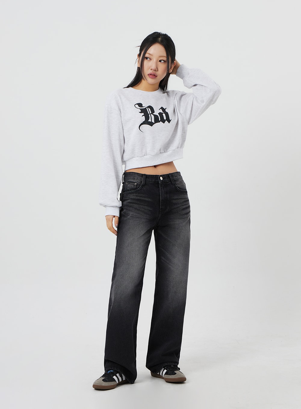 Mid-Rise Bootcut Jeans CF327 in black, full-body angled front on model with hand in hair, washed bootcut denim showing fade gradient, styled with crop sweatshirt.