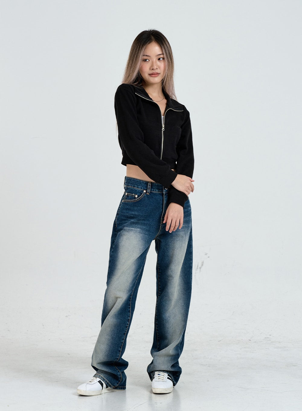Wide Leg Faded Color Denim Pants CO11 in blue gradation, three-quarter front view on model, relaxed wide-fit cotton denim with gradation wash, styled with black crop zip jacket and white sneakers.