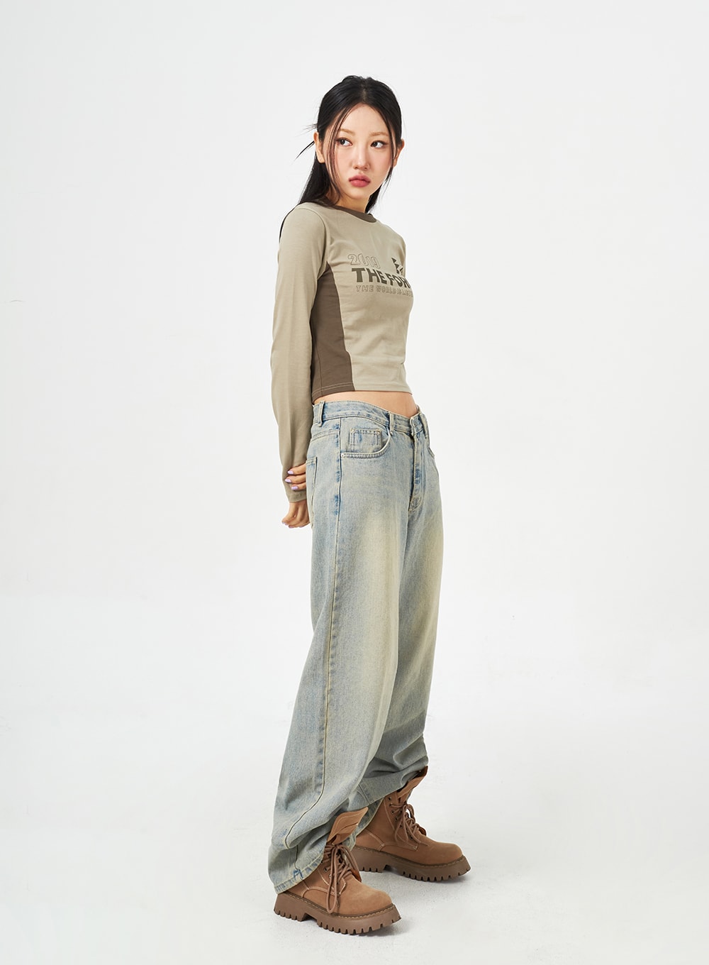 Light Blue Baggy Jeans CM323 in light blue, three-quarter side view on model, wide-leg silhouette with yellow-tinted wash, low rise waistband visible, paired with crop top.