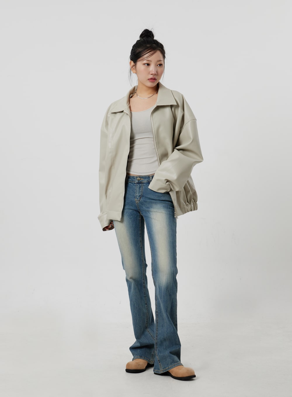 Low Rise Bootcut Jeans CF302 in blue, full-length three-quarter angle on model, low-rise faded denim bootcut, paired with beige zip jacket and white tank, relaxed casual pose.