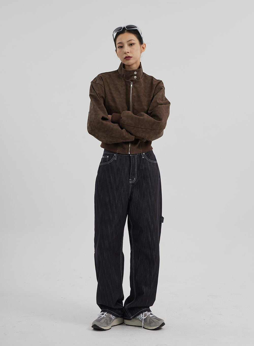 Mid-Rise Baggy Jeans CF307 in dark indigo, full-body front view on model with arms crossed, relaxed wide-fit denim with white contrast stitch detail, paired with brown cropped jacket.