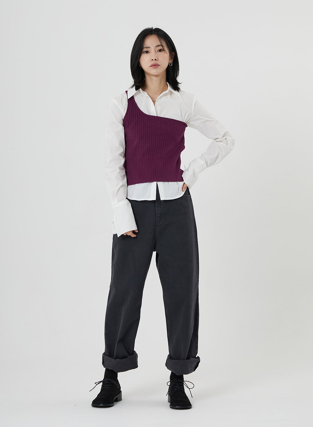 Maxi Denim Pants ON23 in charcoal grey, full-body front shot on model hand on hip, wide-fit denim with cuffed hem, paired with white long-sleeve shirt and purple asymmetric knit vest.