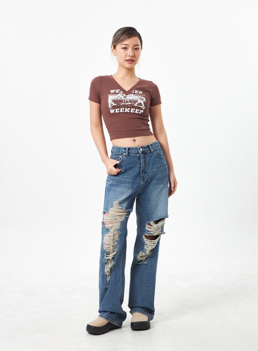 Wide Ripped Jeans CA304 in medium blue, full-body front on model, wide-leg street-style denim with bold ripped knee details and hand in pocket, worn with brown crop tee.