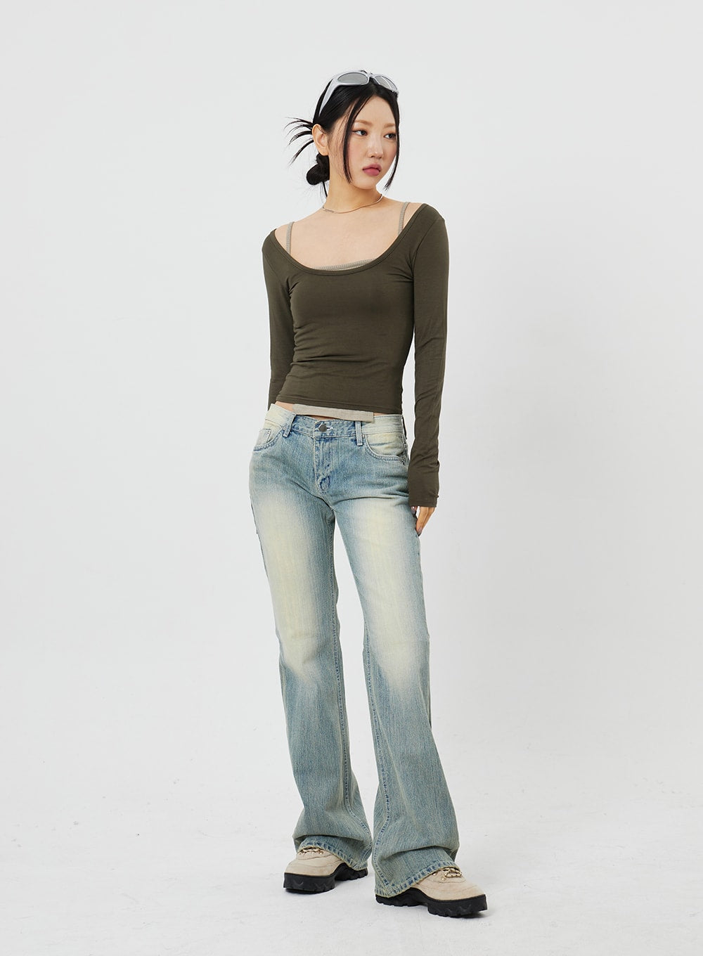 Low Rise Bootcut Jeans CF315 in light blue, front three-quarter shot on model looking away, low waist with visible contrast fading at hips, bootcut silhouette, chunky boots.