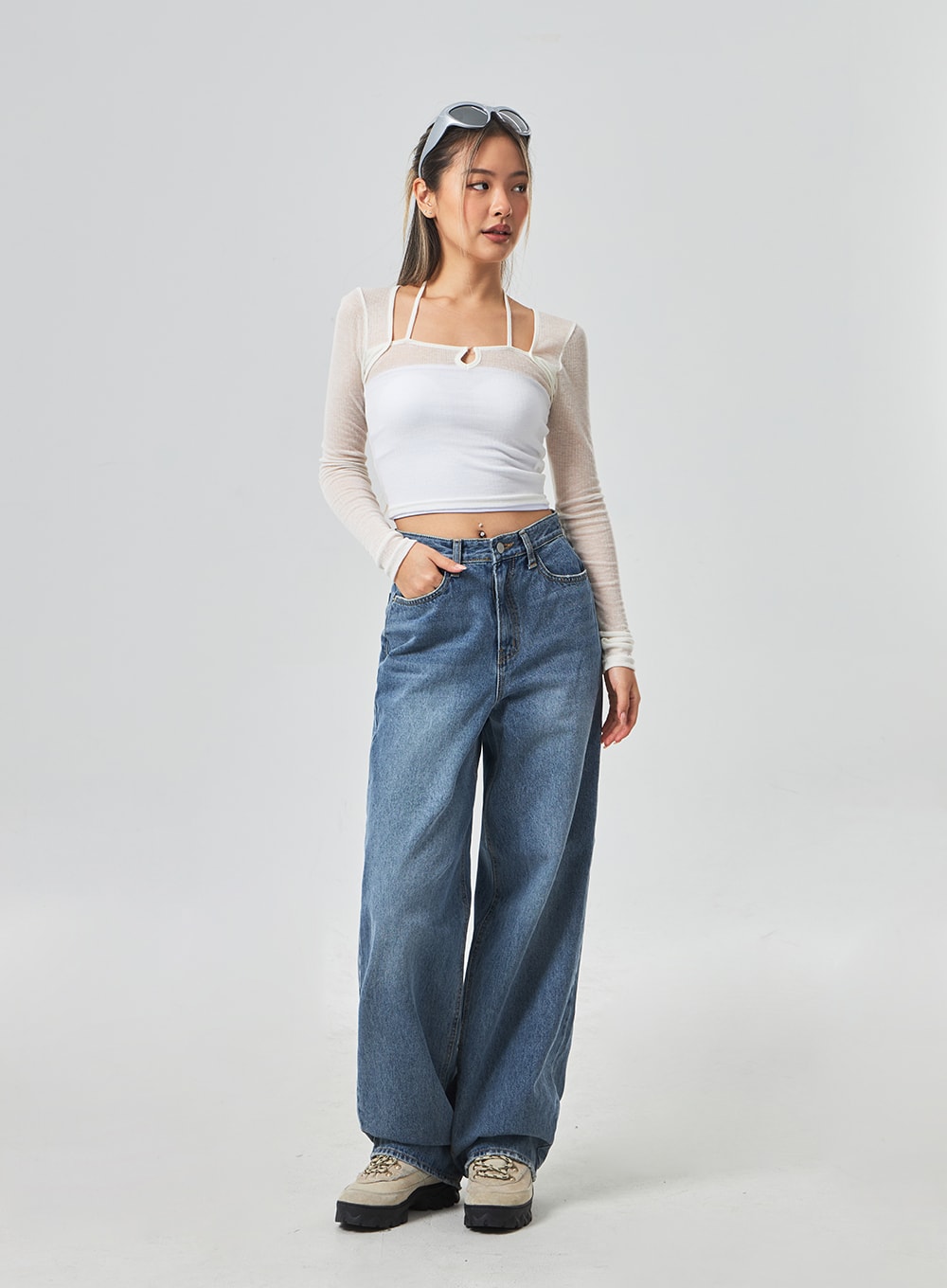 Wide Leg Mid-Wash Jeans CM331 in mid-wash blue, three-quarter front view on model looking aside, high-rise wide-leg denim with subtle fade, styled with white crop top and chunky shoes.