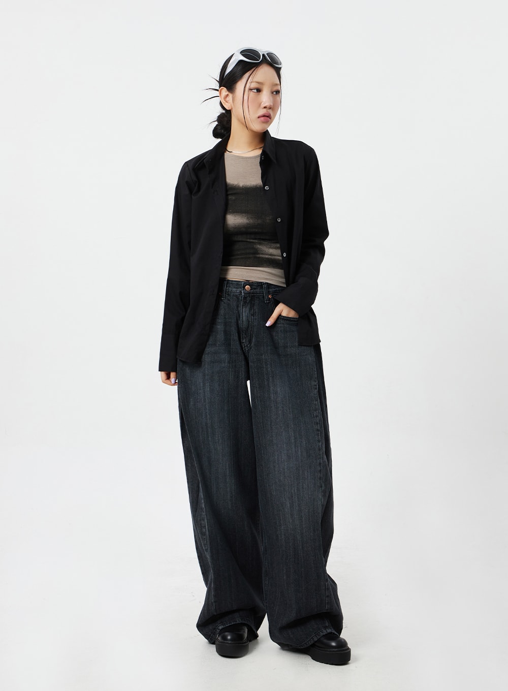 Mid-Rise Baggy Jeans CM324 in washed black denim, three-quarter front angle on model with hand in pocket, voluminous wide leg, styled with open black overshirt.