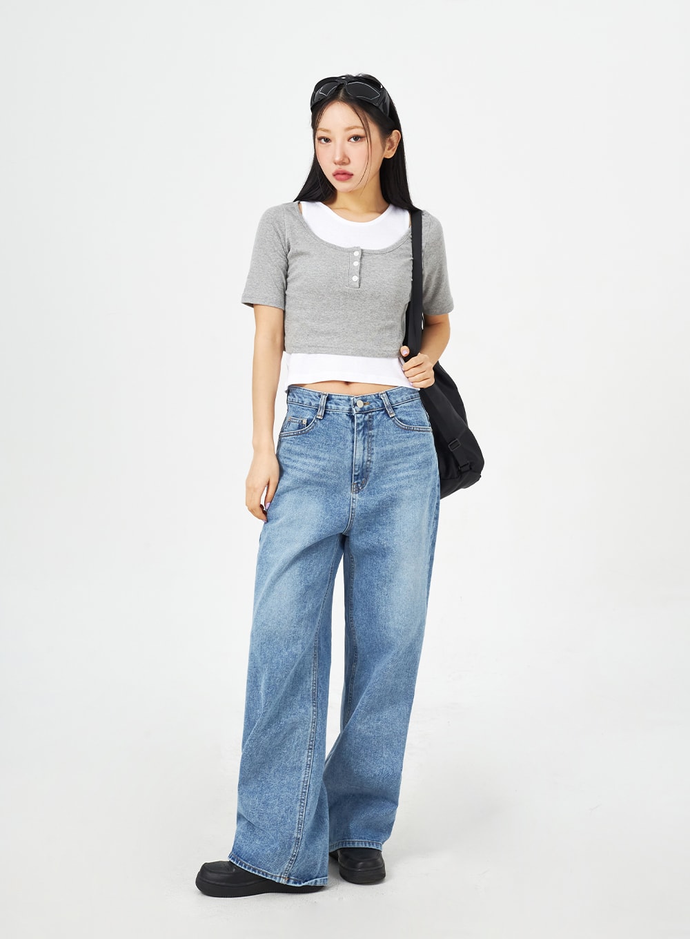 Mid-Wash Bootcut Jeans CM323 in mid blue, full-length slight side view on model, wide-fit high-rise washed denim, styled with grey crop top and black shoulder bag.
