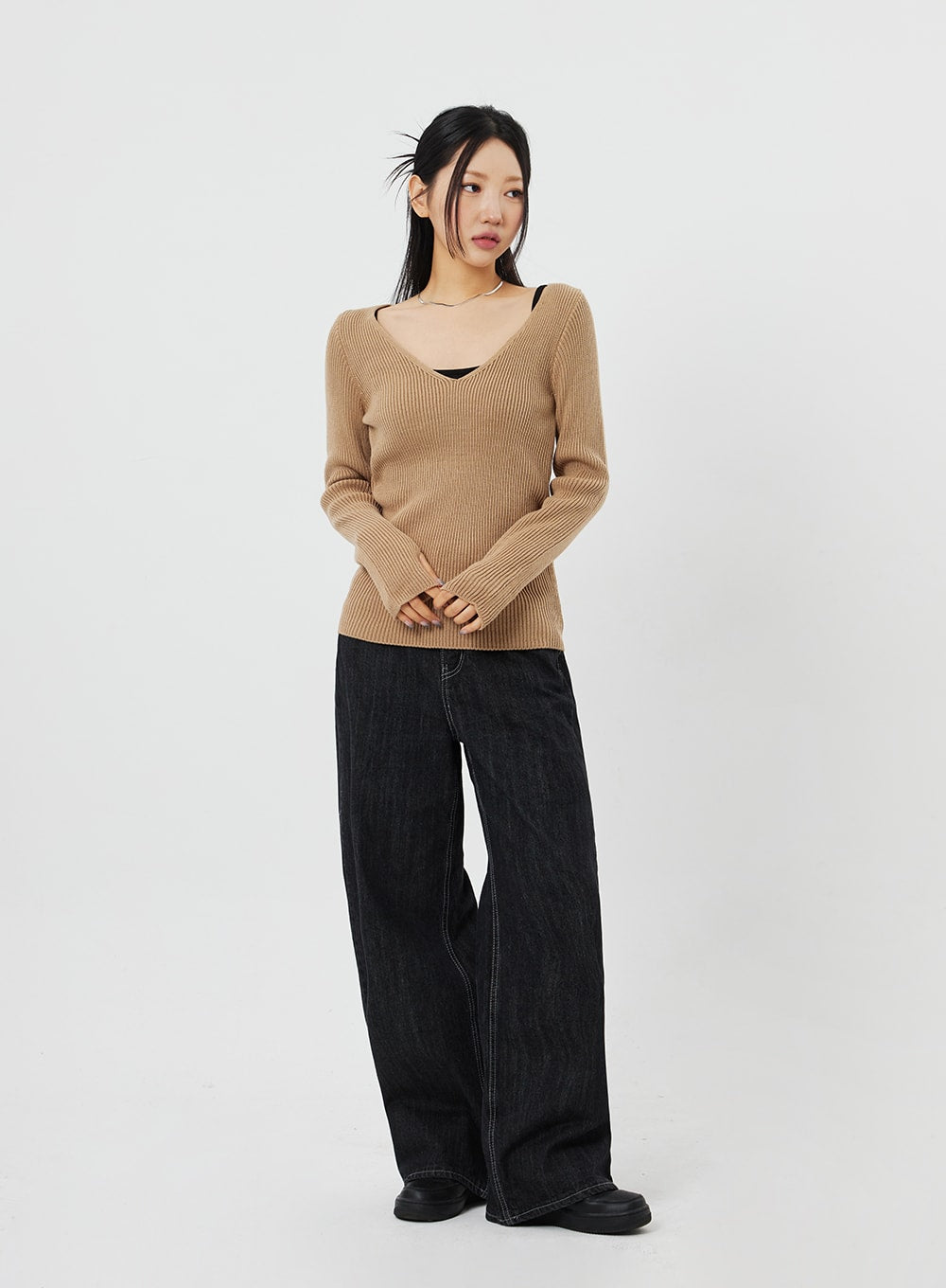 Straight Leg Jeans CF315 in black, full-body front on model with hands clasped, wide-fit cotton denim showing contrast stitching, paired with camel ribbed knit.