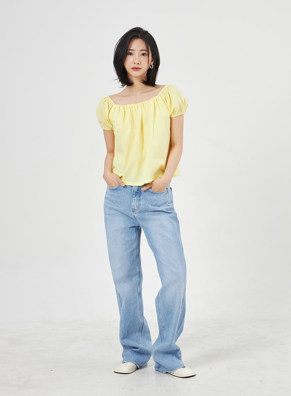 Light Wash Jeans OA310 in light blue, front full-body shot on model standing straight, wide-leg washed cotton denim with side slit hem, paired with yellow puff-sleeve top.