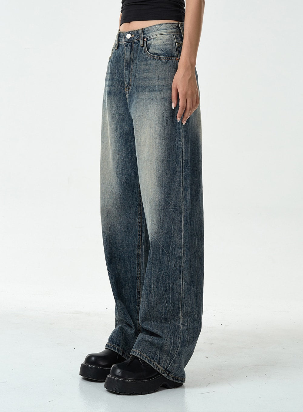 Washed Denim Pants CG10 in dark blue, side view close-up on model, straight wide-leg denim showing whisker fading and crinkled texture along thigh, mid-rise waistband detail visible.