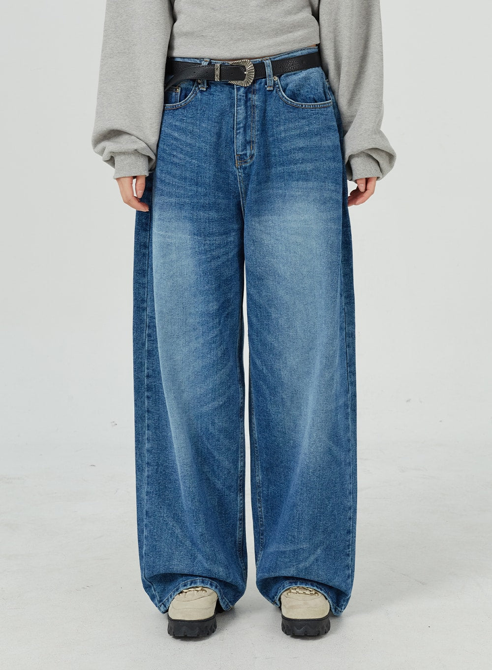 Oversized Jeans Unisex CM321 in blue, waist-to-ankle front close-up, wide-leg cotton denim with visible washed creases and black western belt detail.