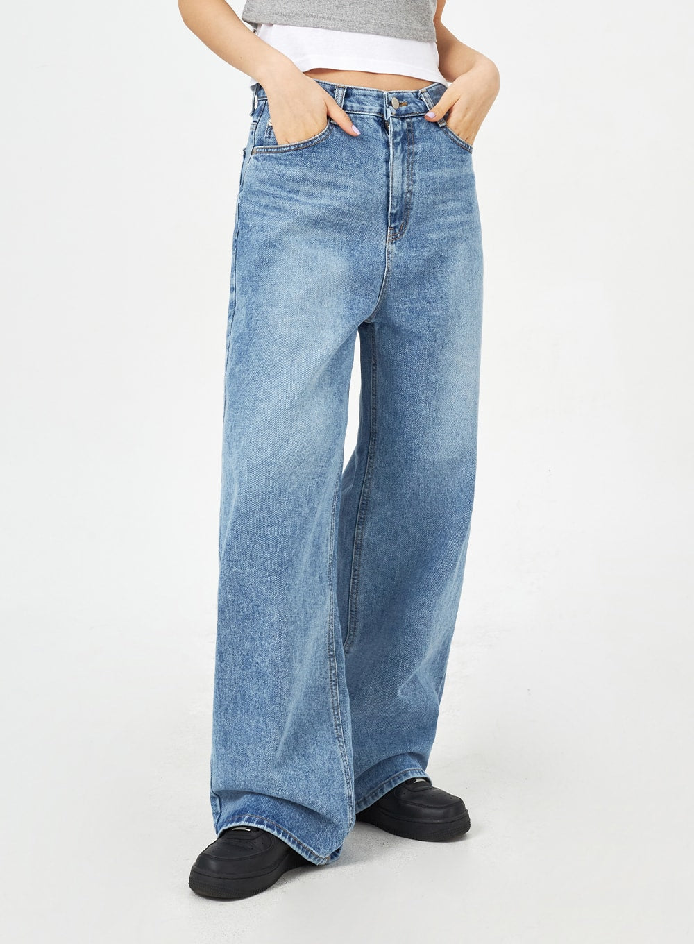 Mid-Wash Bootcut Jeans CM323 in mid blue, angled front close-up from waist to hem, high-rise wide-fit washed denim with front pockets and bootcut leg silhouette.