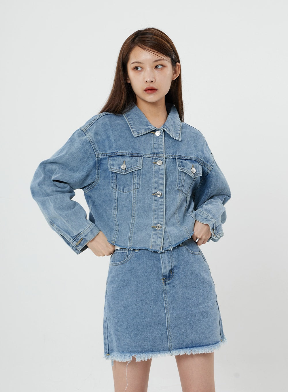 Sienna Crop Jeans Jacket CS21 in light blue, front three-quarter close-up on model, raw hem crop cut and chest pockets highlighted, paired with frayed-hem denim mini skirt.
