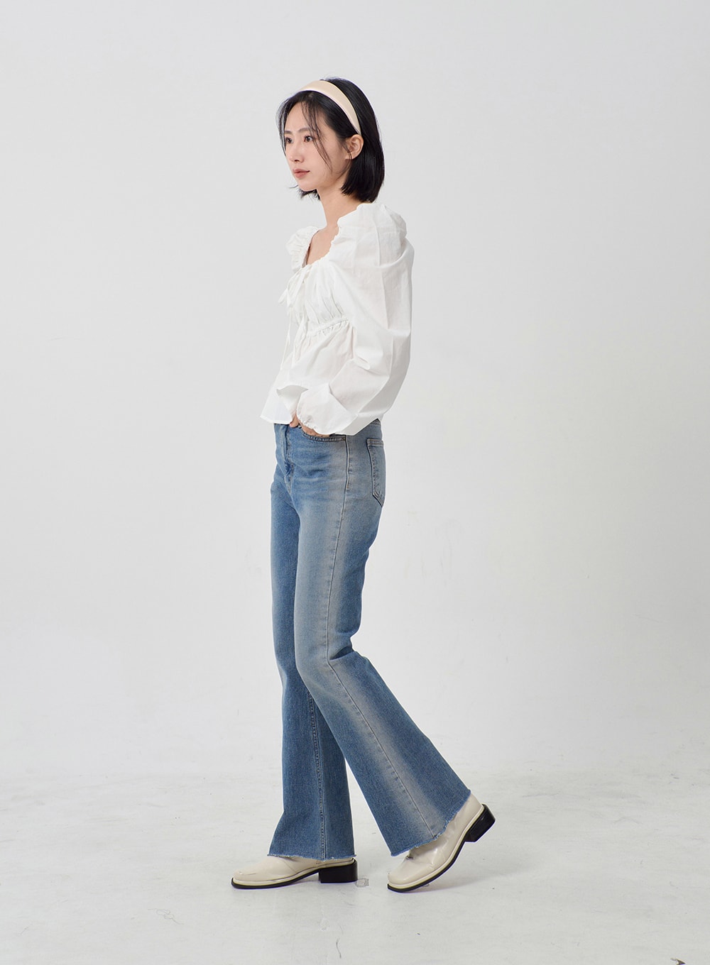 LEWKIN Light Washed Bootcut Jeans OD27 in light blue, side full-length view on model, slim-fit cotton denim with subtle wash, flared hem, paired with white ruffle blouse and loafers.