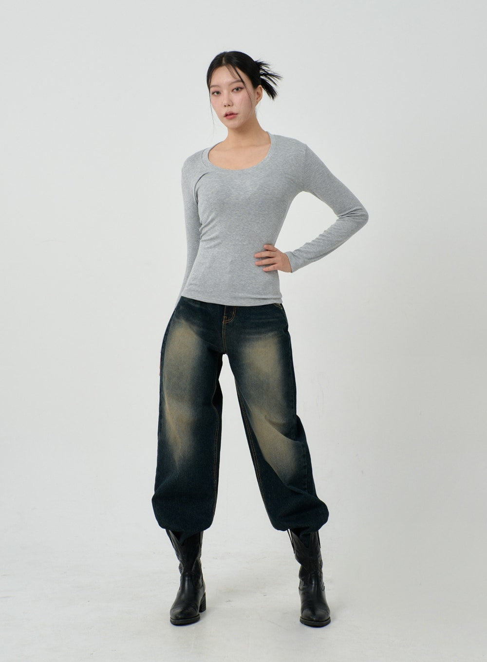 Vintage Washing Baggy Jeans ID23 in dark indigo, full-body front on model with one hand on hip, wide baggy leg and vintage yellow-tinted wash, styled with grey scoop-neck long-sleeve and black knee boots.