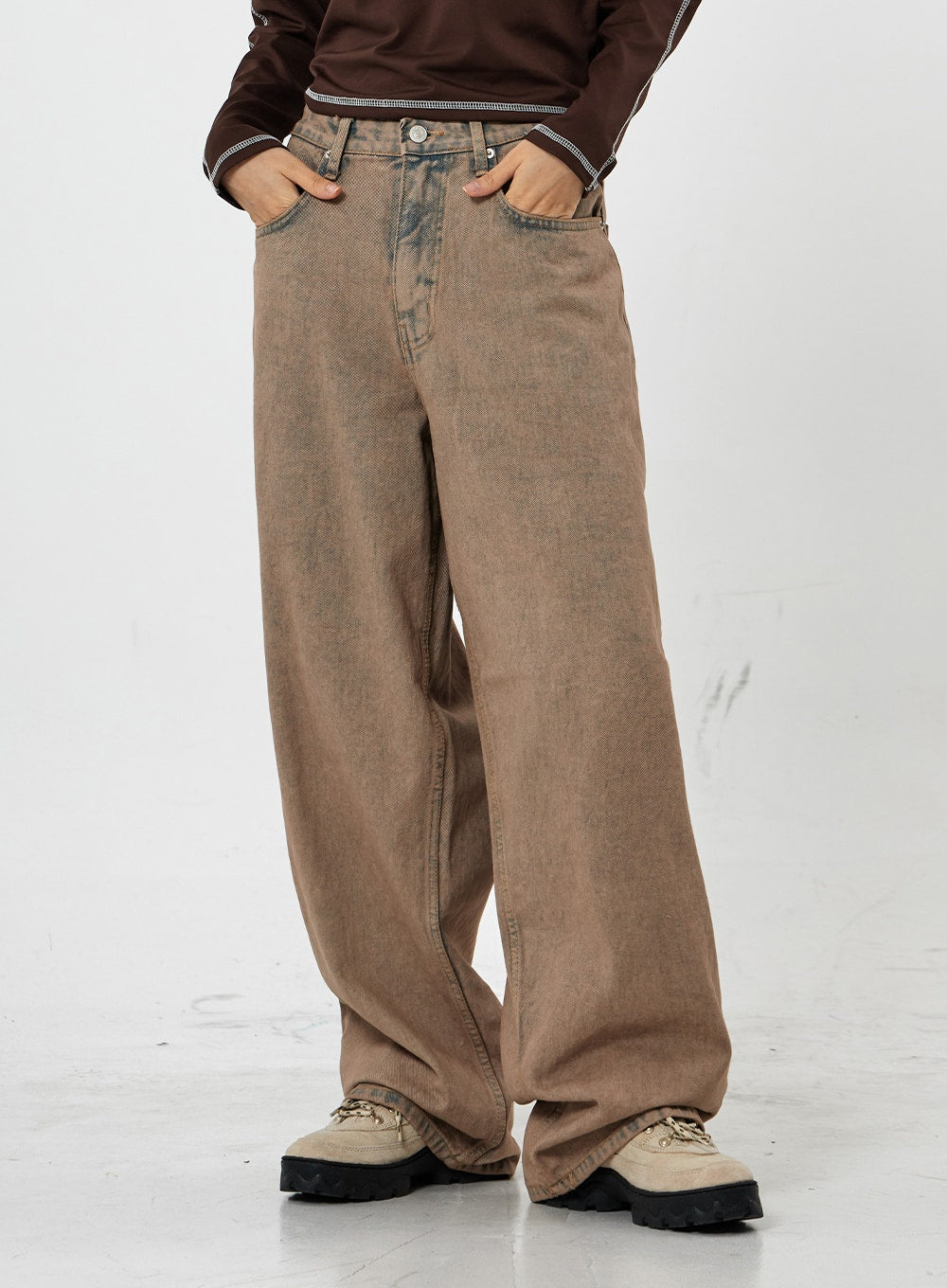 Raemon Wide Jeans Unisex CS21 in brown acid-wash, front waist-to-hem close-up on model with hands in pockets, low-rise waistband and extra-wide leg denim detail visible.