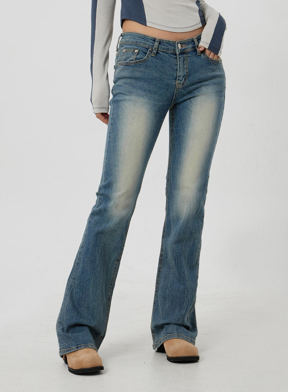 Low Rise Bootcut Jeans CF302 in blue, mid-body front close-up on model, low-rise waistband with button fly and coin pocket, sun-faded wash detail, flared bootcut leg.