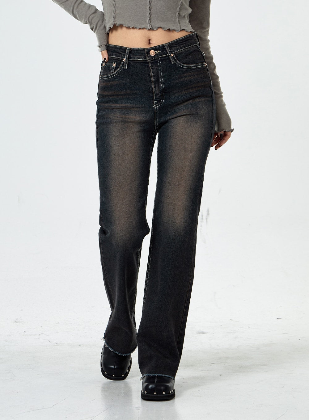 Basic Washed Bootcut Jeans CS07 in black washed denim, front mid-shot walking pose, high-rise waistband with contrast stitching, slim bootcut flare, frayed raw hem, grey crop top above.