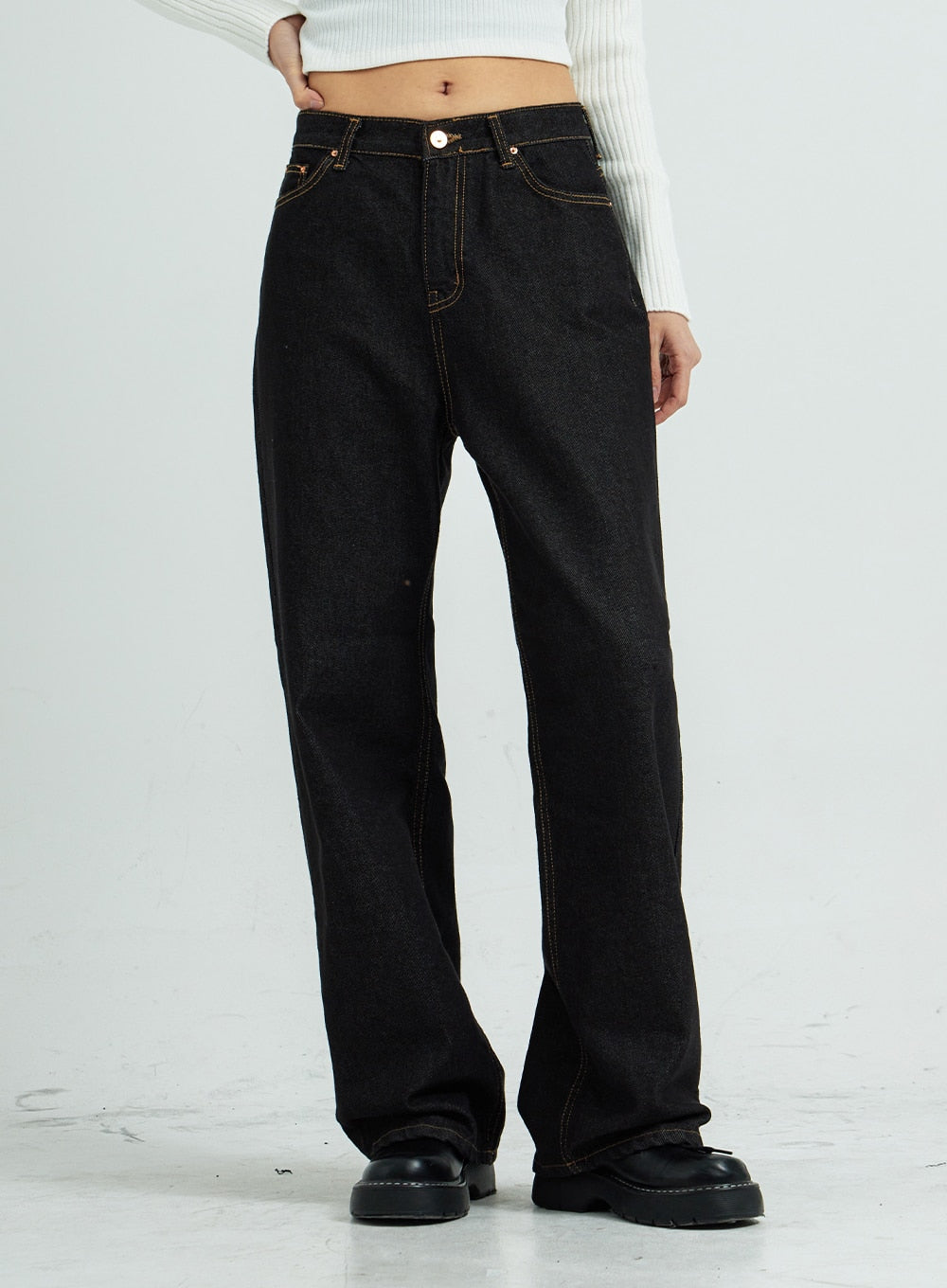 Pepe Wide Pants CS15 in black, angled front close-up on model, wide-leg cotton denim highlighting gold contrast topstitching and five-pocket construction, with black platform shoes.