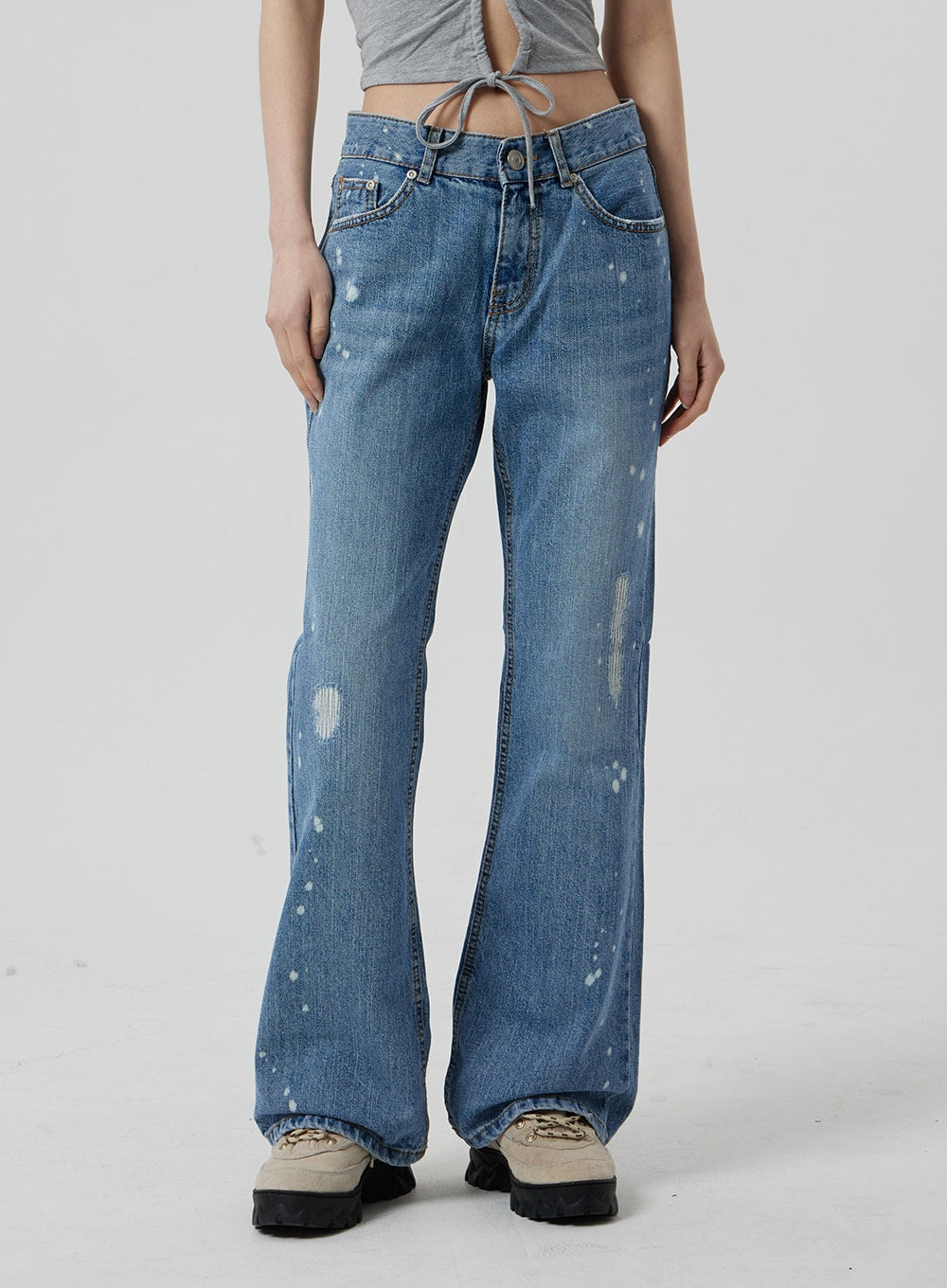 Low Rise Bootcut Jeans CF309 in blue denim, front mid-shot on model from waist to hem, low-rise button fly with five-pocket construction, paint-splatter and abrasion distressing, flared bootcut opening.
