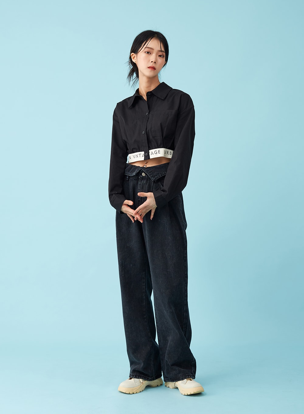 Four Buttoned Open Black Jeans CU8 in washed black, front full-body on model with hands clasped, folded open waistband detail with logo belt, wide-leg washed denim, black crop shirt styling.