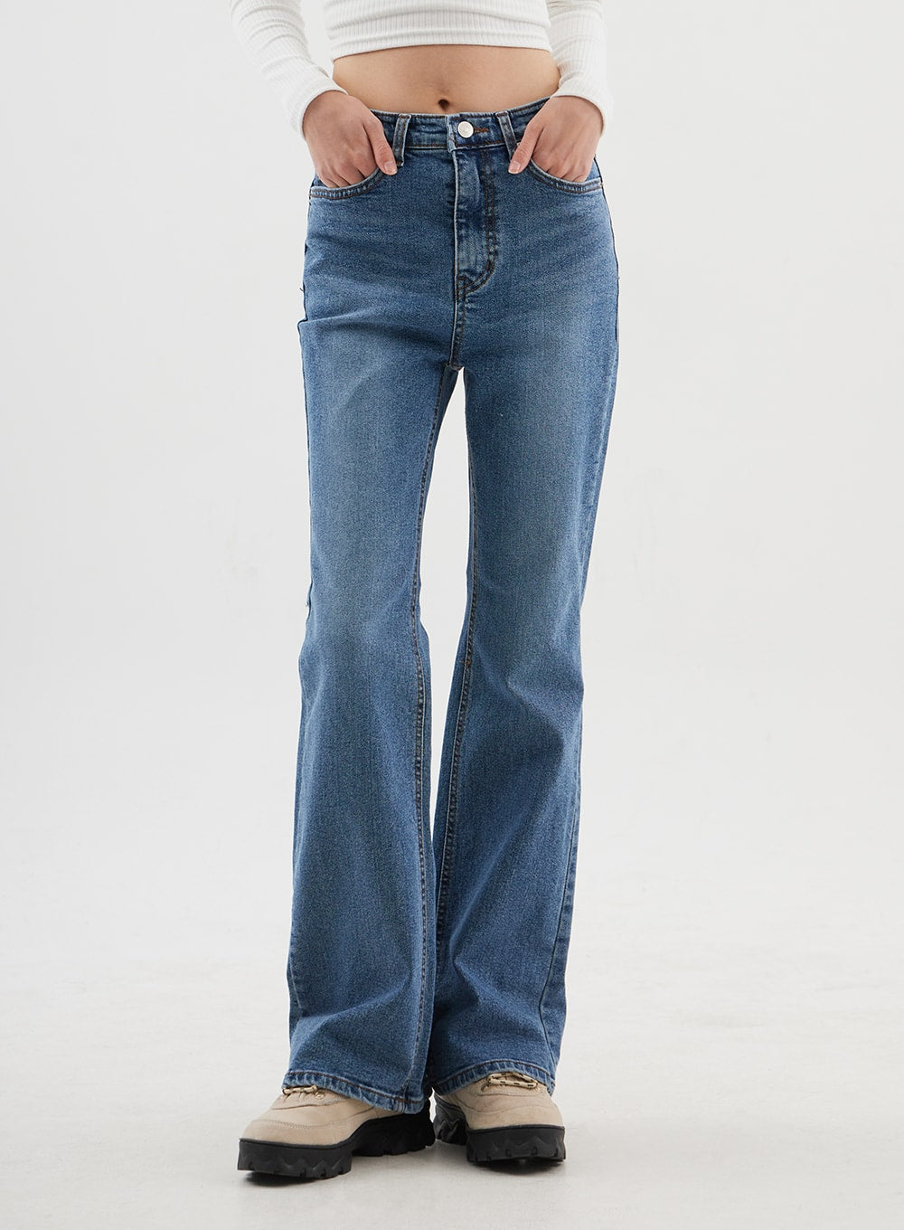Slim Fit Bootcut Jeans CJ311 in medium blue, front close-up cropped at thigh on model, hands in front pockets, mid-rise waistband with belt loops and button detail, washed denim texture.