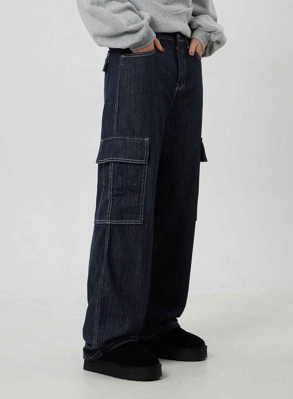 Wide Cargo Jeans CF302 in dark indigo, side view close-up on model, oversized flap cargo pocket with contrast white stitch highlighted, wide-leg denim silhouette and relaxed drape.