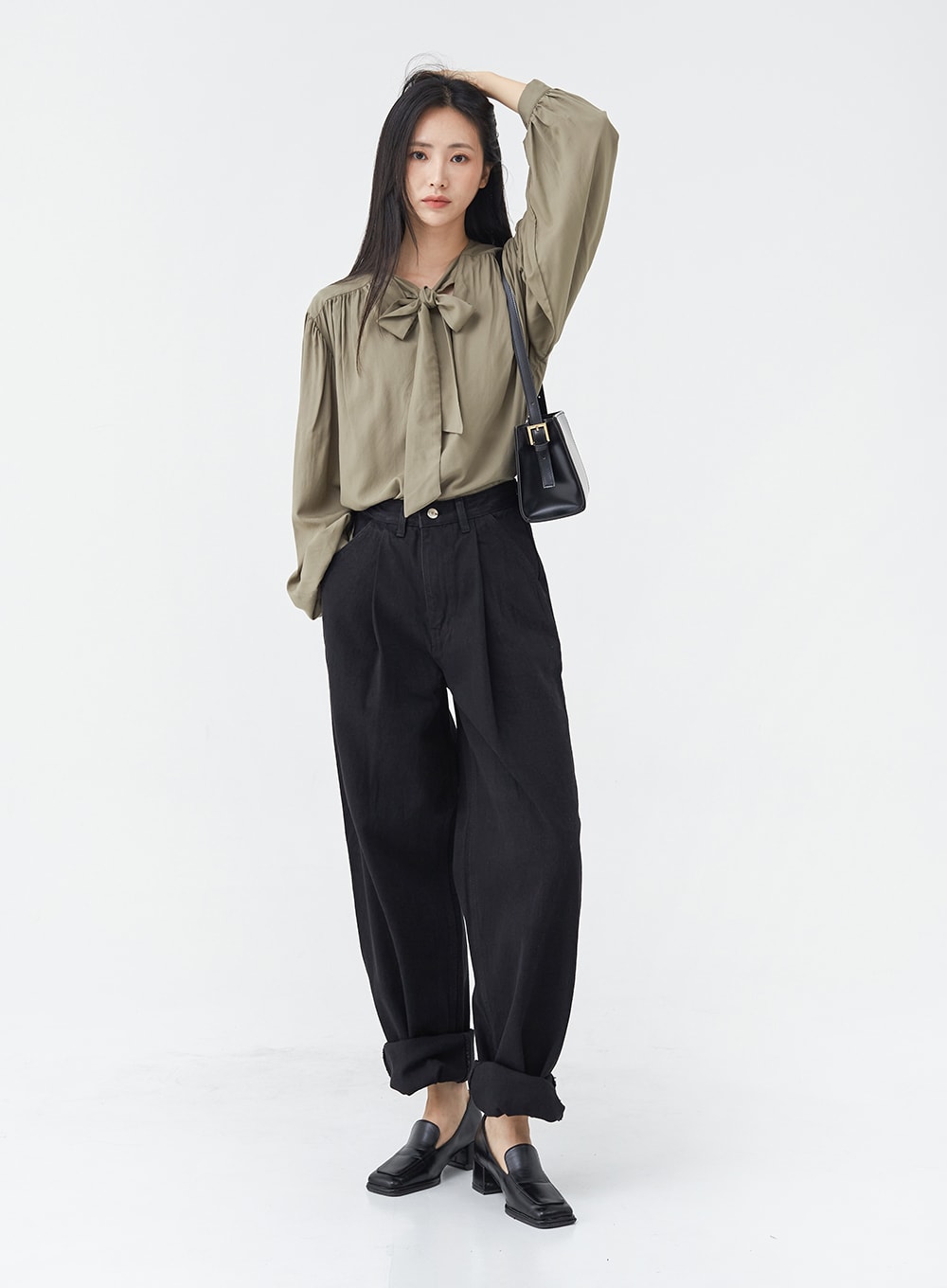 Pintuck Black Jeans OG18 in black, full-body front shot on model, wide-fit cotton pintuck jeans with rolled cuffs, styled with olive bow blouse, crossbody bag, and black loafers.
